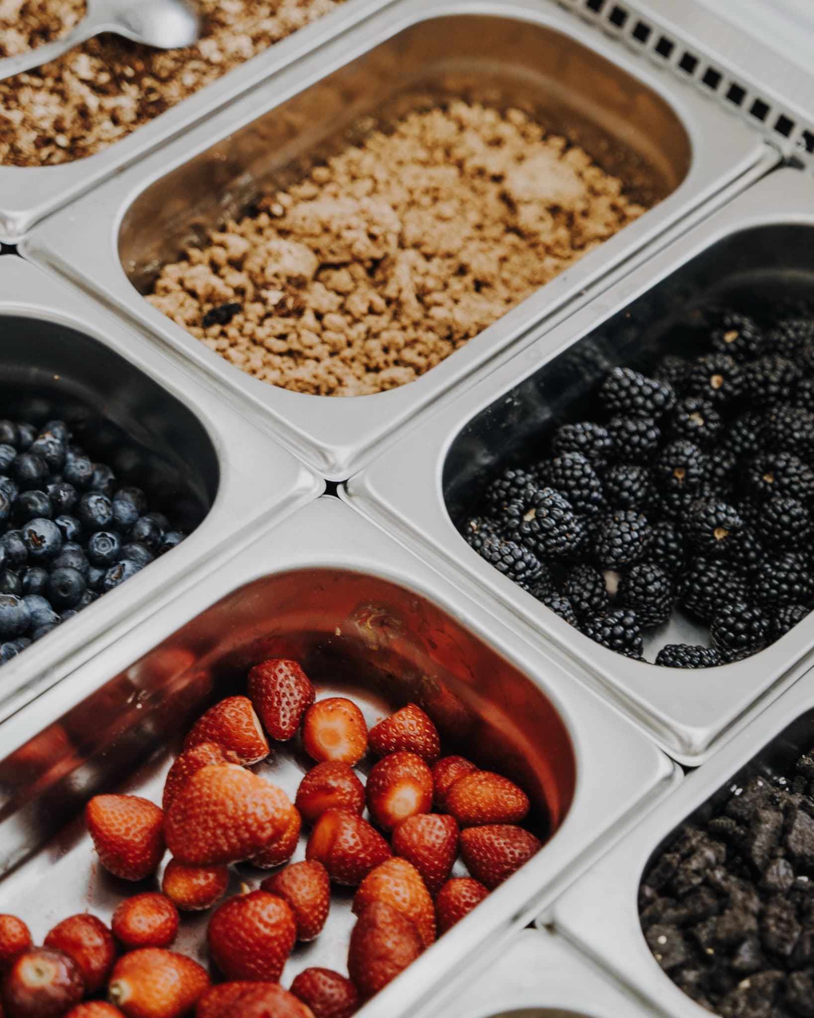 Bandejas de fresas, arándanos, moras y granola en la barra de toppings